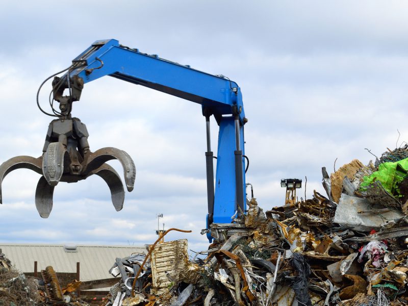 Blue hydraulic Clow Crane used for picking up scrap metal at recycling yard